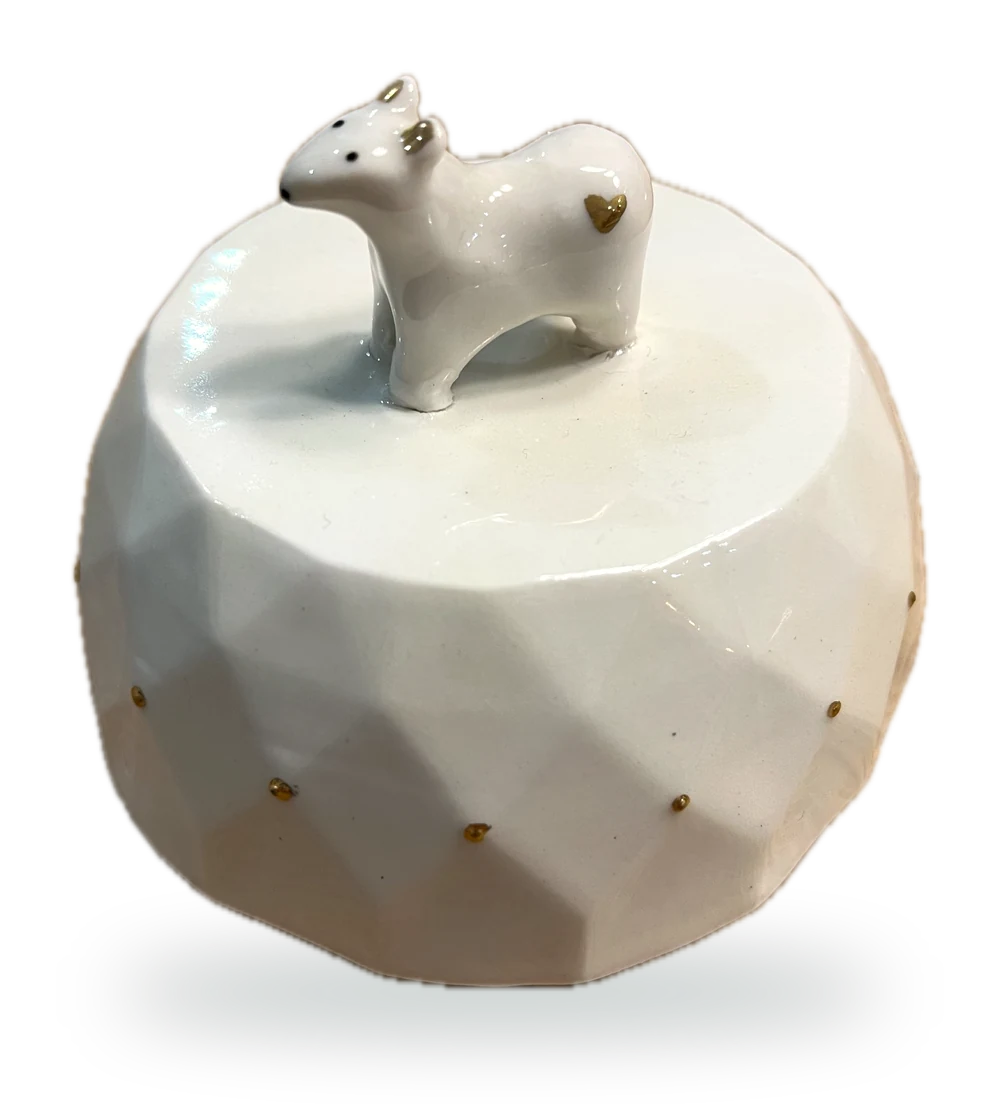 La boîte à musique ronde en porcelaine facettée, son ourson aux oreilles et au cœur dorés, et ses pois d'or